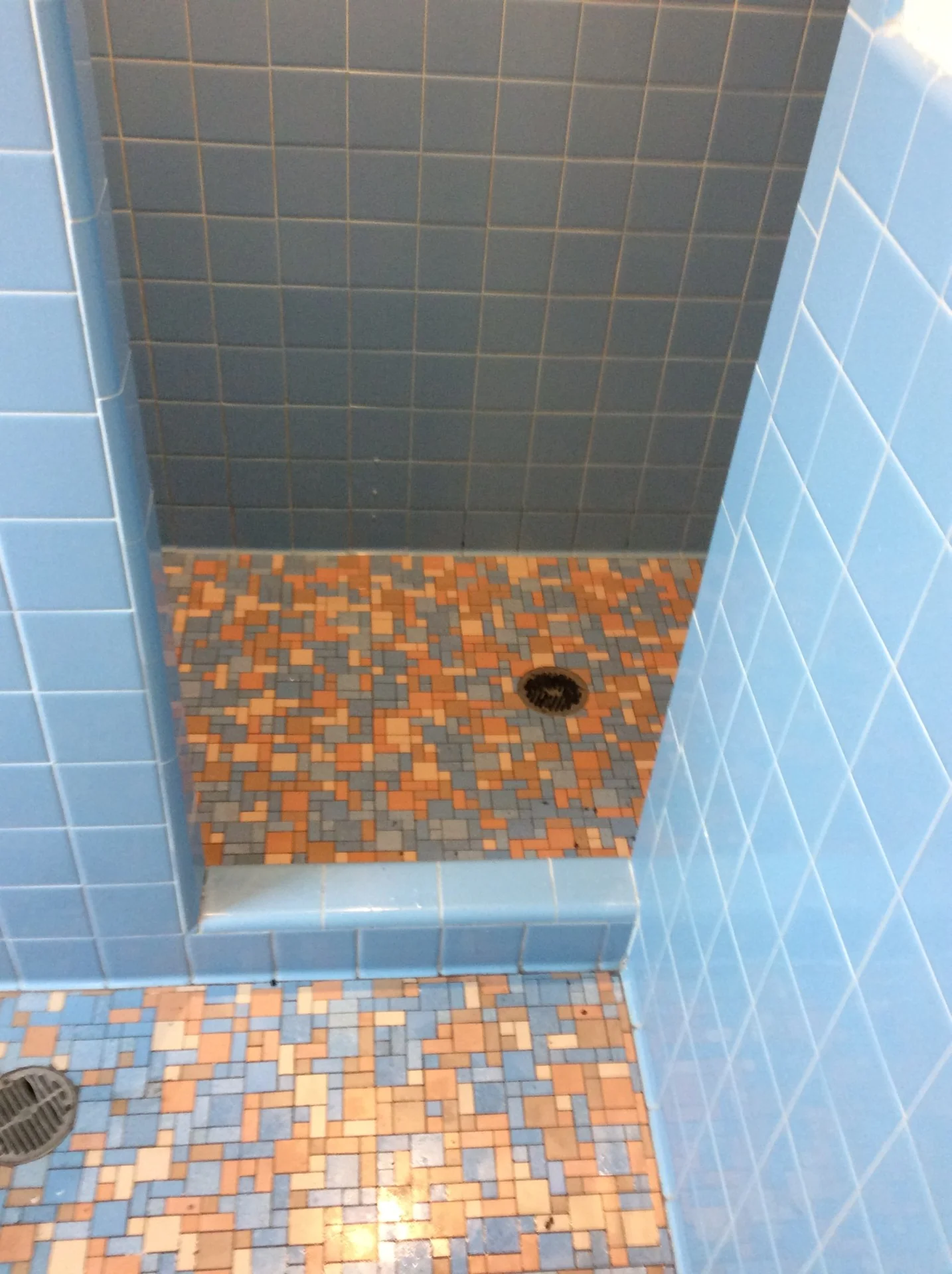 Dated dormitory shower tile and floor before refinishing