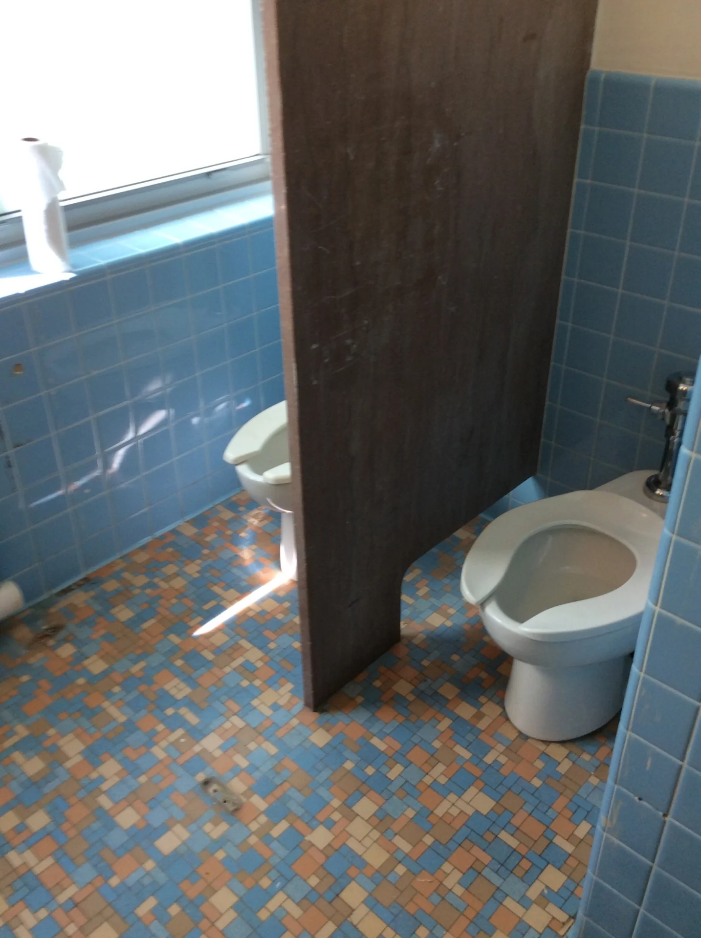Dormitory restroom partitions, tile walls, and floor before refinishing
