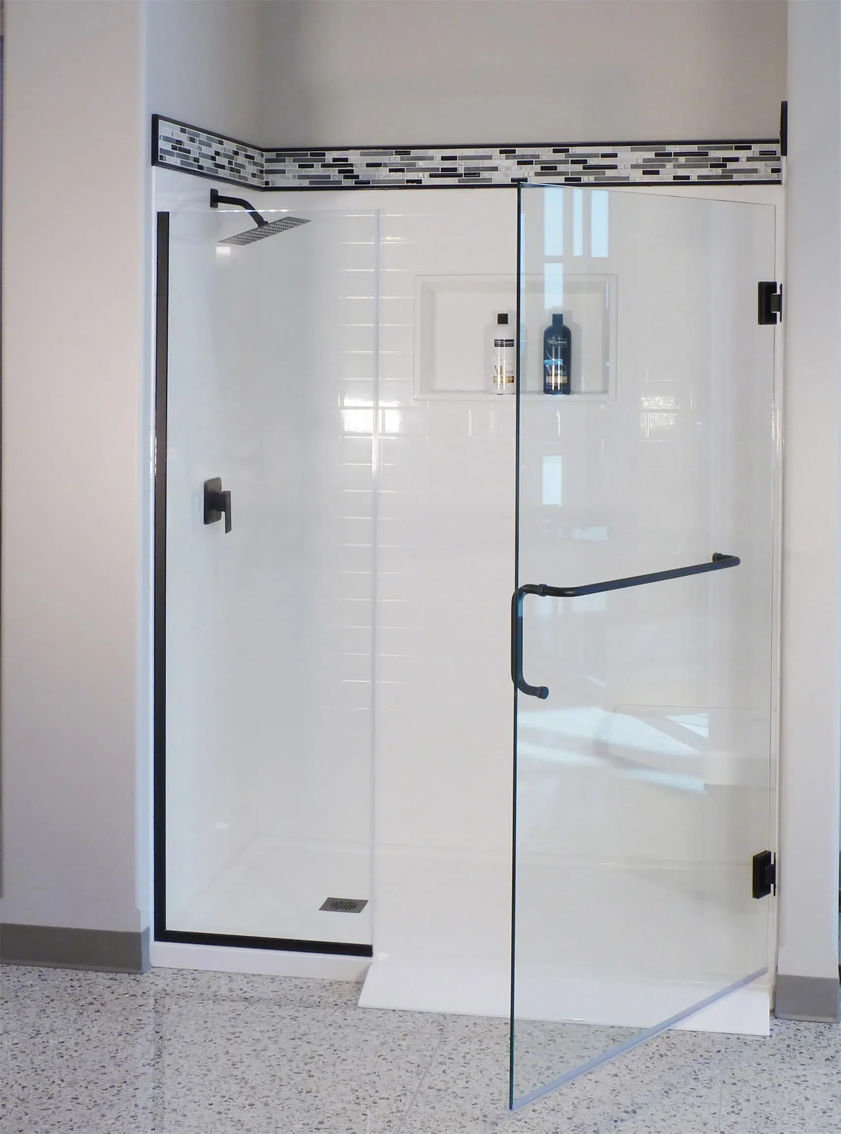 Completed shower with frameless glass door and black fixtures