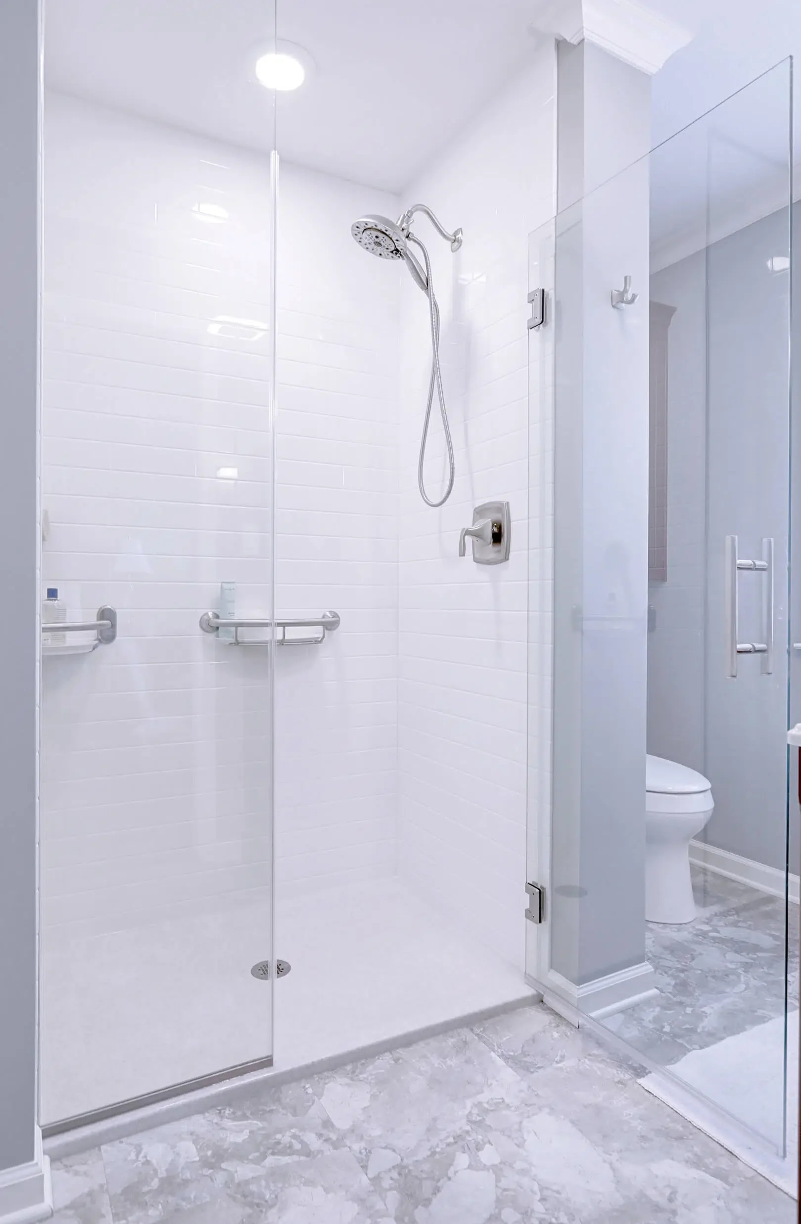 Bright tub-to-shower conversion with frameless glass enclosure and handheld shower
